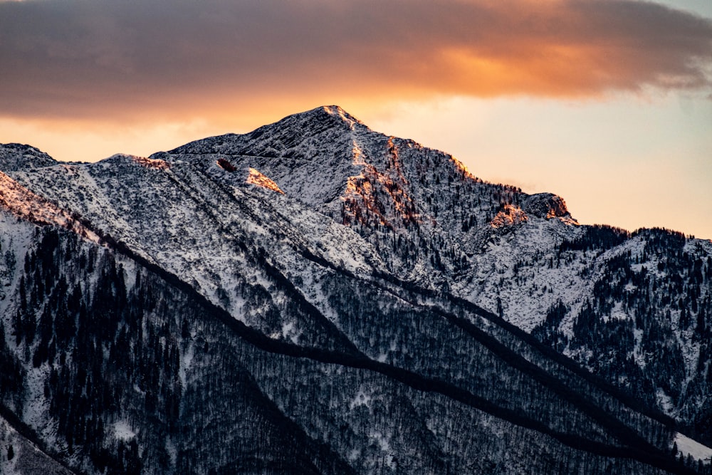 a mountain covered in snow under a cloudy sky