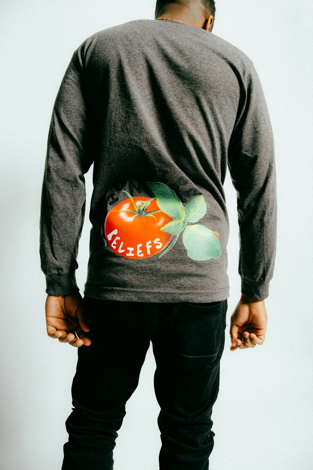 a man wearing a long sleeve shirt with a tomato on it