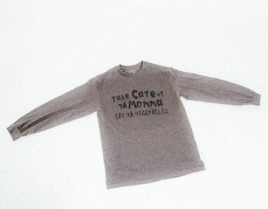 A long-sleeved gray shirt with text on the front that reads 'Take Care of Ya Momma Eat Ya Vegetables'.