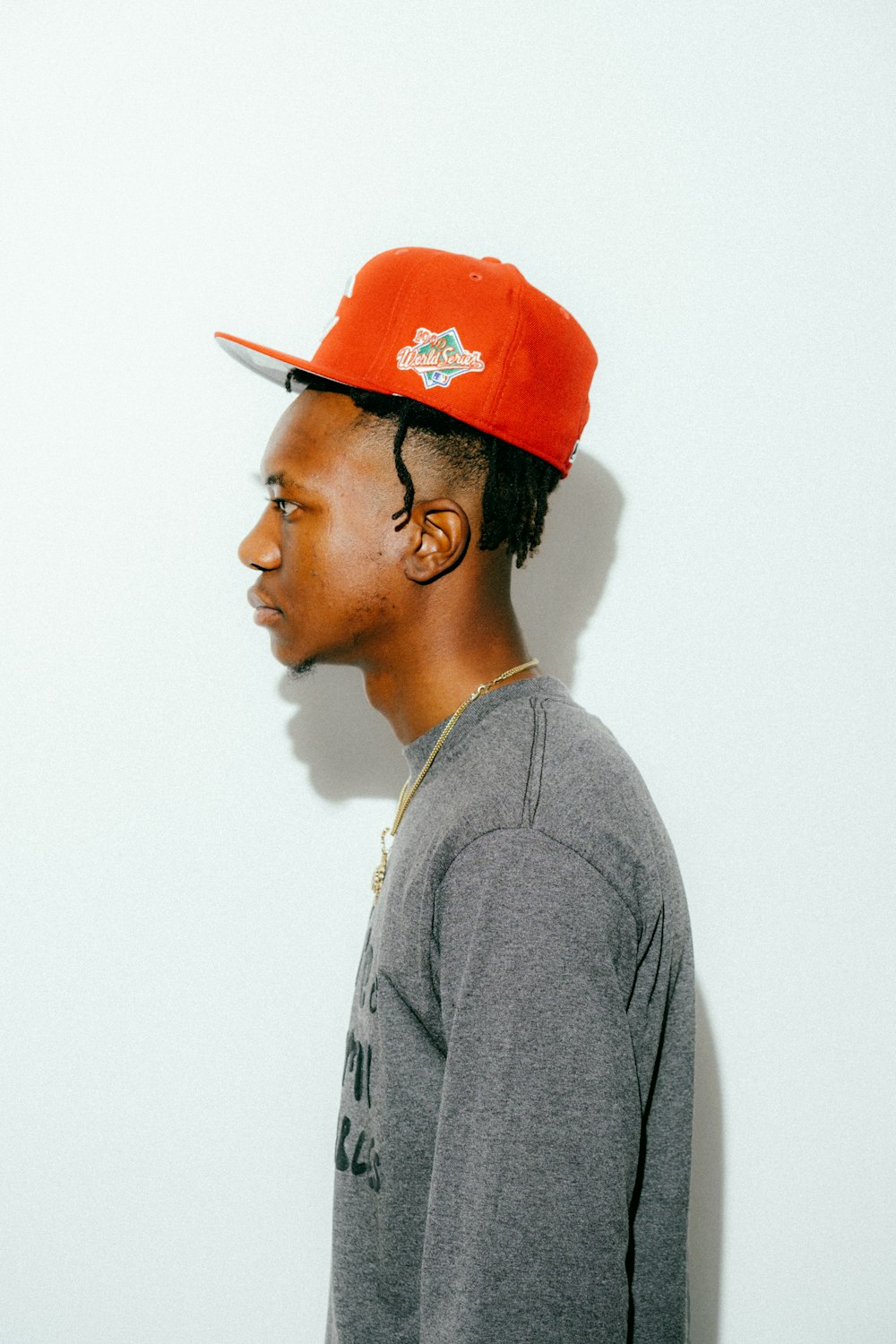 a young man wearing a red hat and grey shirt