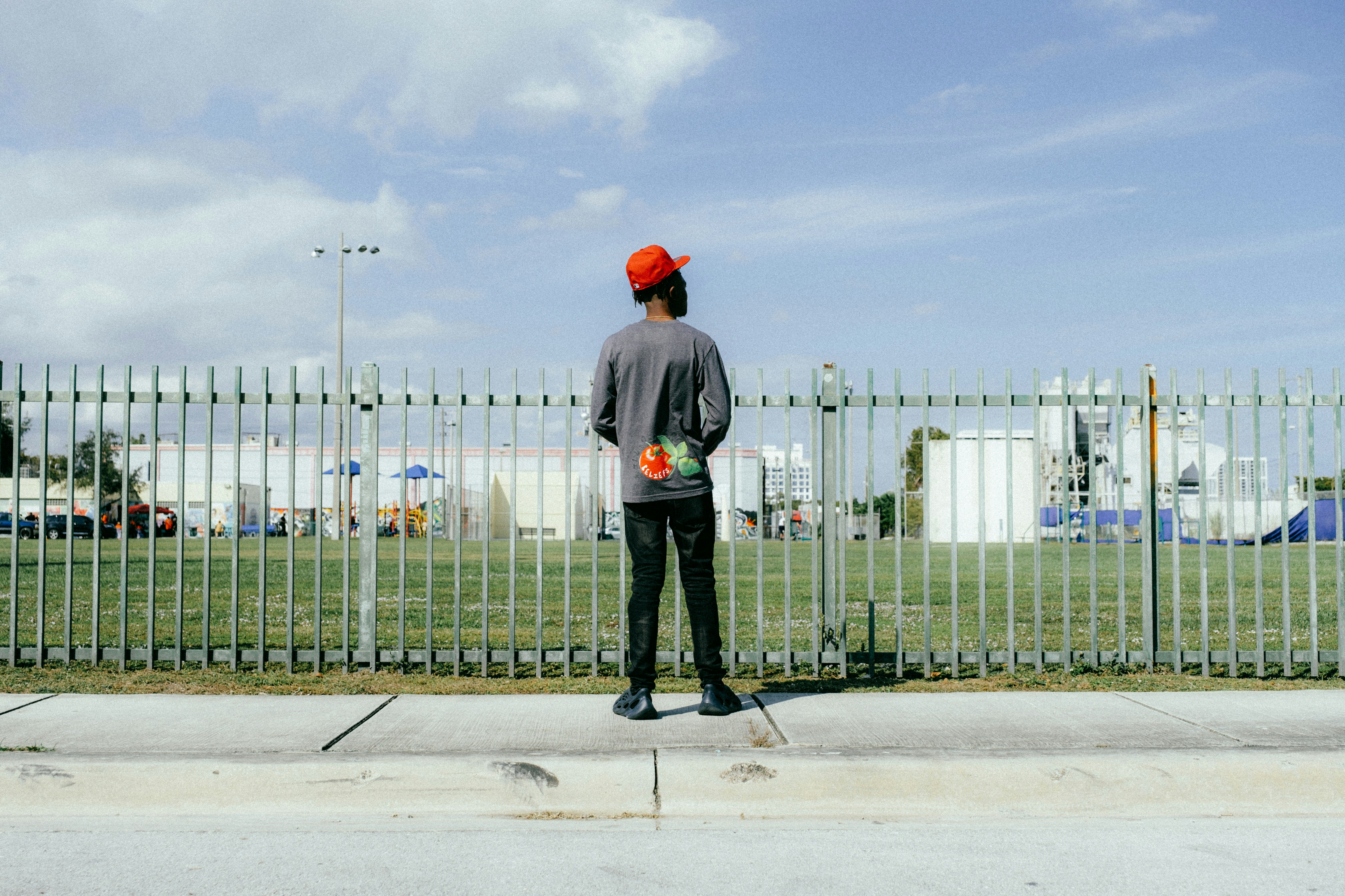 a man standing on the side of a road next to a fence
