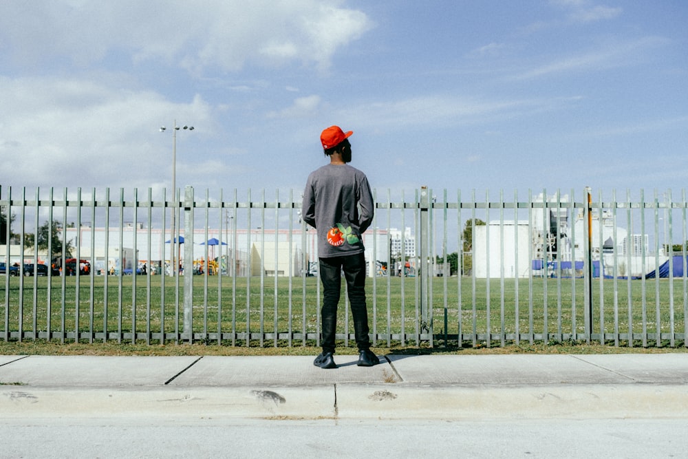 a man standing on the side of a road next to a fence