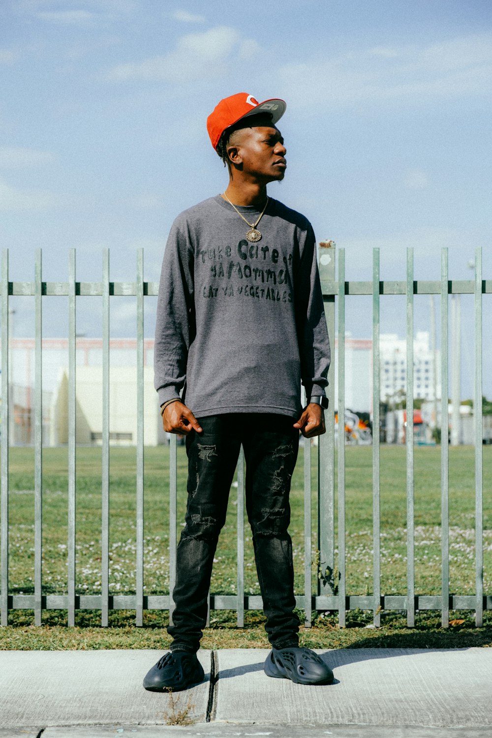 a man standing on a skateboard in front of a fence