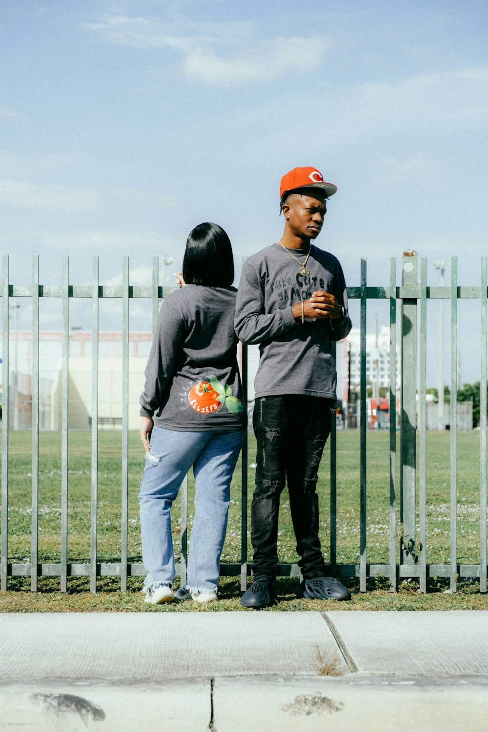 a couple of people standing next to a fence