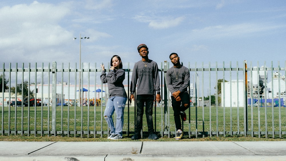 a group of people standing in front of a fence