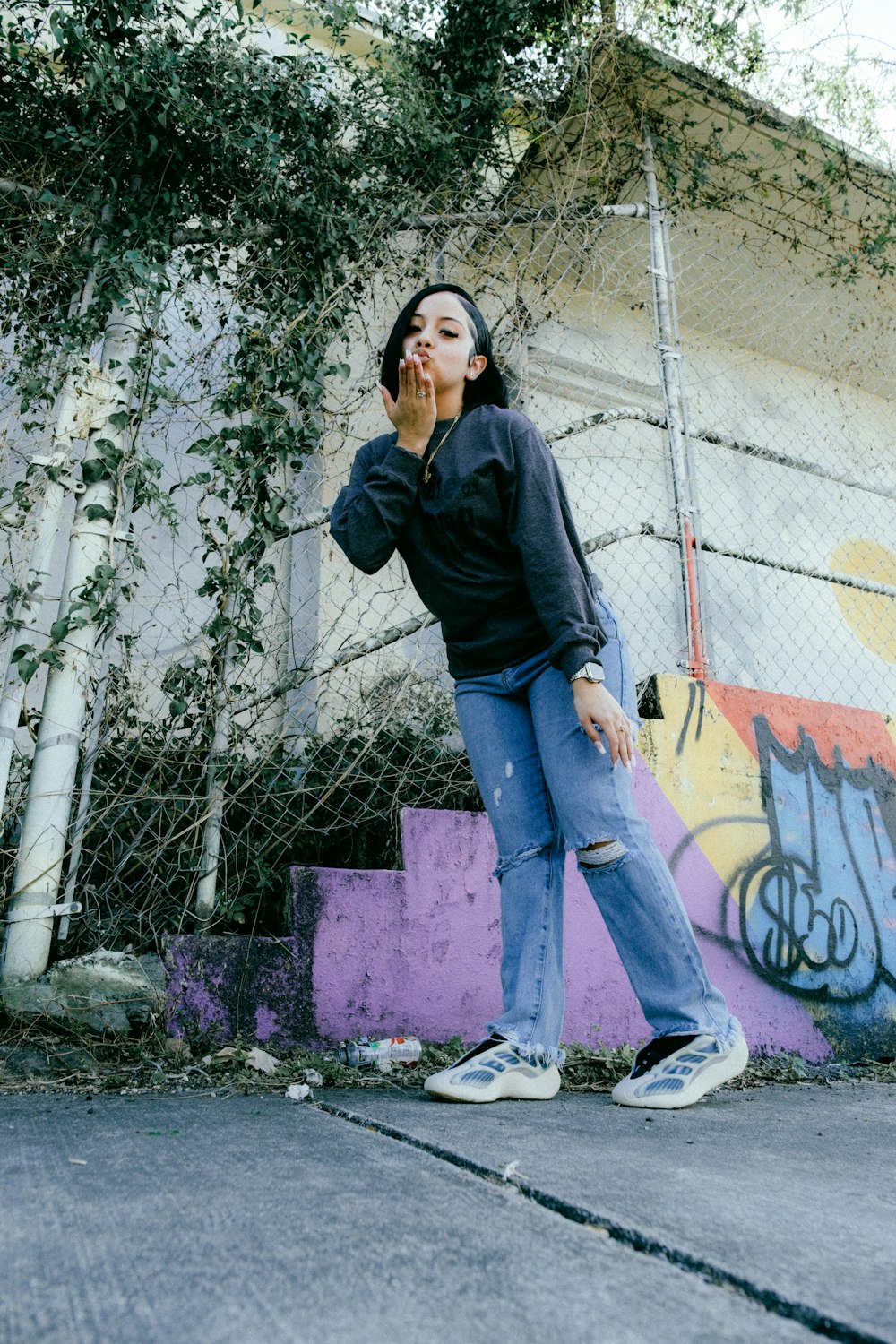 a woman standing in front of a graffiti covered wall