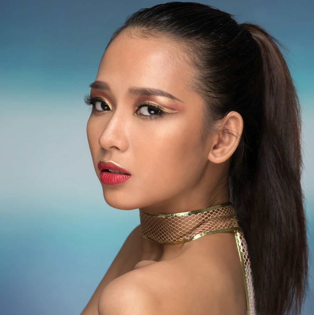 a woman with a gold choker and red lipstick