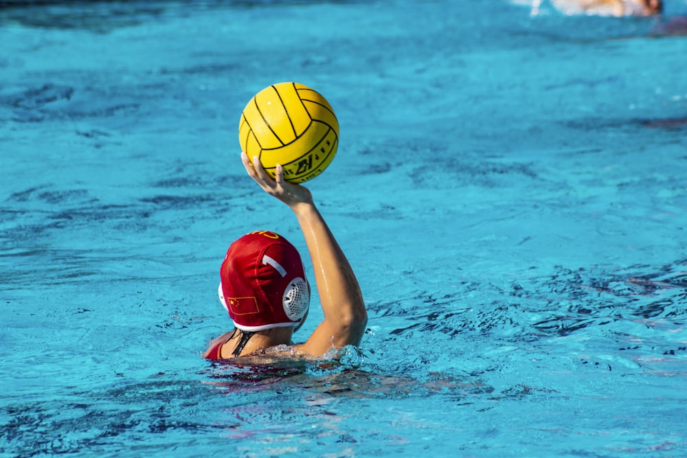 eine Person in einem Pool mit einem Ball in der Hand