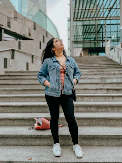 Street-style shot of a young woman wearing oversized Crossgear t-shirt and leggings, standing confidently on urban stairs