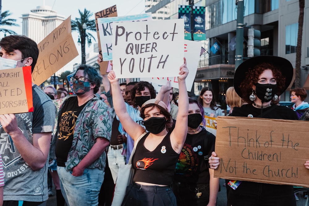 a group of people holding signs and wearing masks