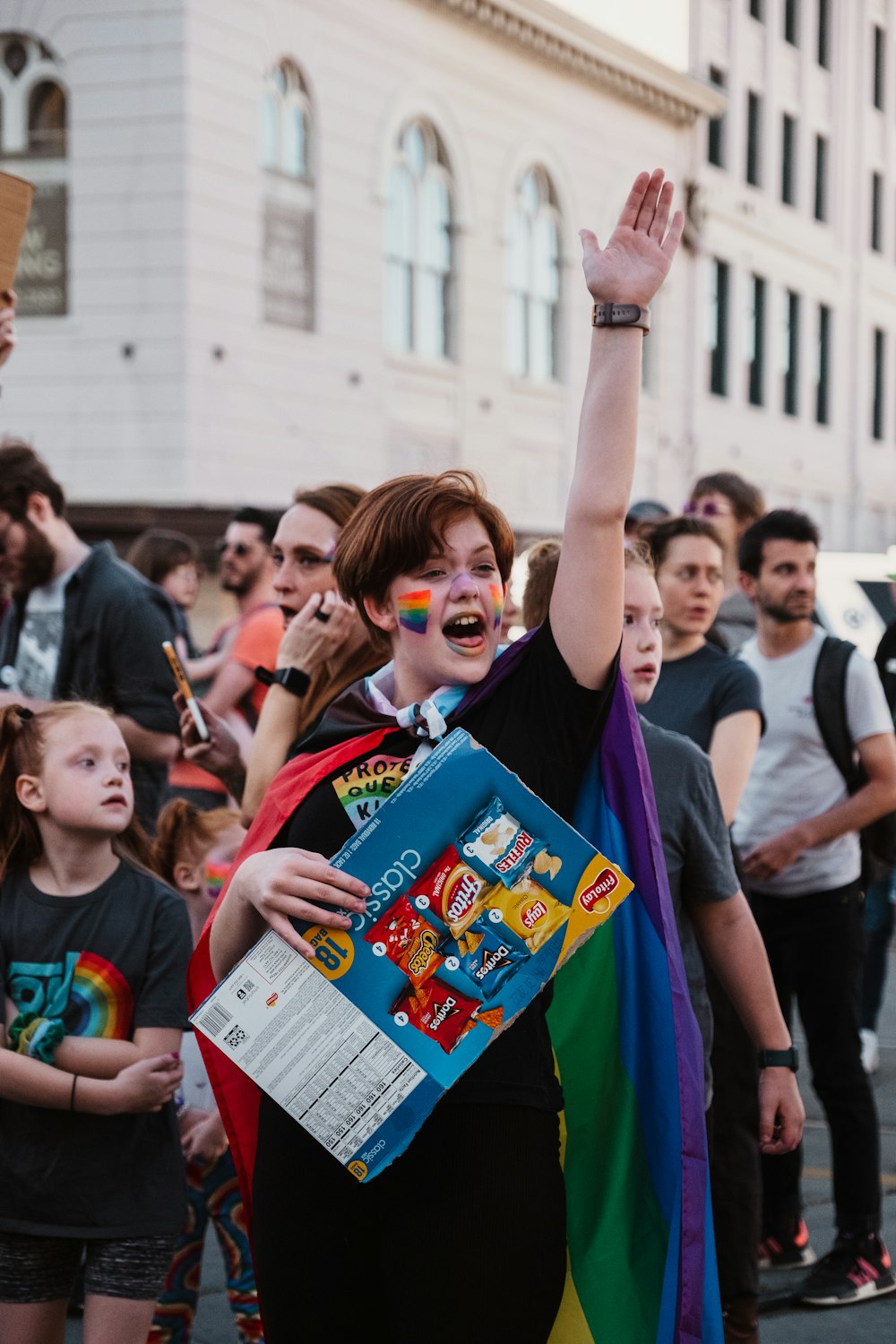 Una donna che indossa un mantello color arcobaleno e tiene in mano un libro