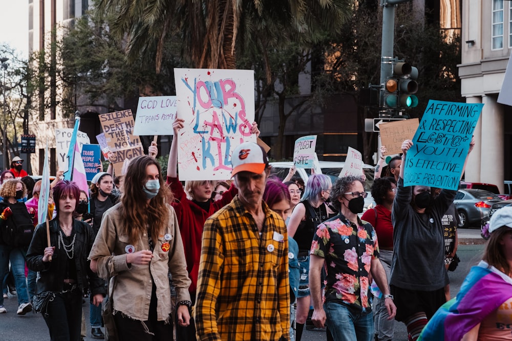 a group of people walking down a street holding signs