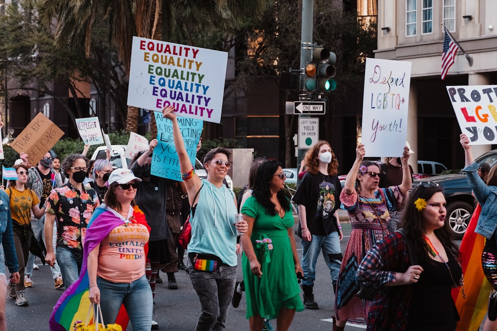 a group of people walking down a street holding signs