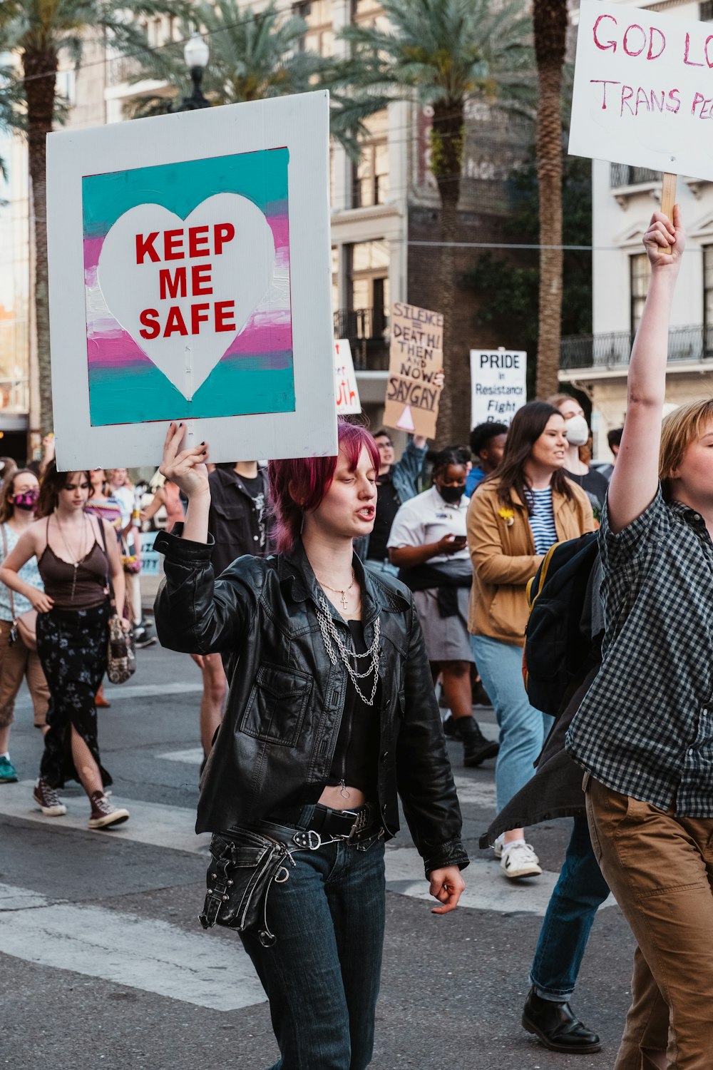 a group of people walking down a street holding signs