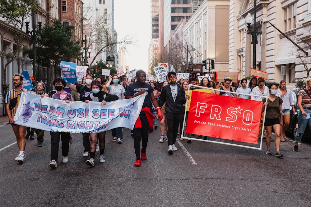 a group of people walking down a street holding a banner