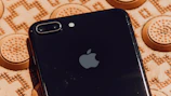 Close-up of a sleek black iPhone with a shiny gold case on a dark reflective surface