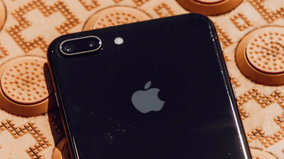 Close-up photo of a sleek black iPhone 14 Pro displayed on a glossy black surface with golden accents.