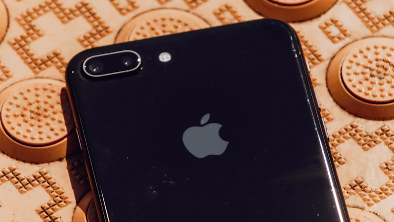 Close-up of a sleek black iPhone with a shiny gold case on a dark reflective surface