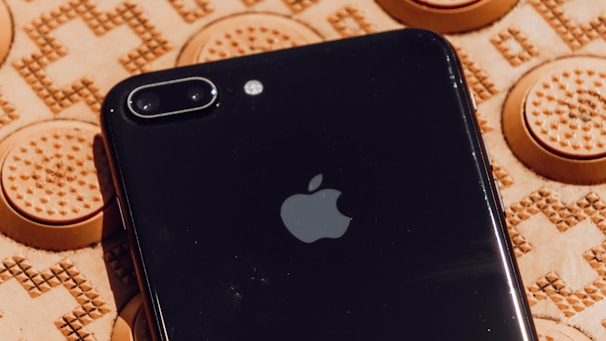 Close-up of a smartphone wrapped in a matte black tech-themed skin with subtle circuit patterns.