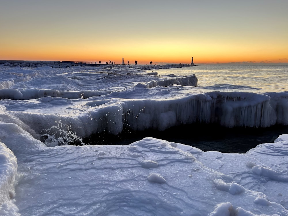 the sun is setting over the water and ice