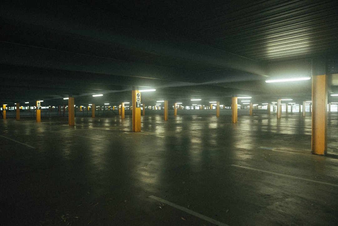 an empty parking lot at night with lights on,