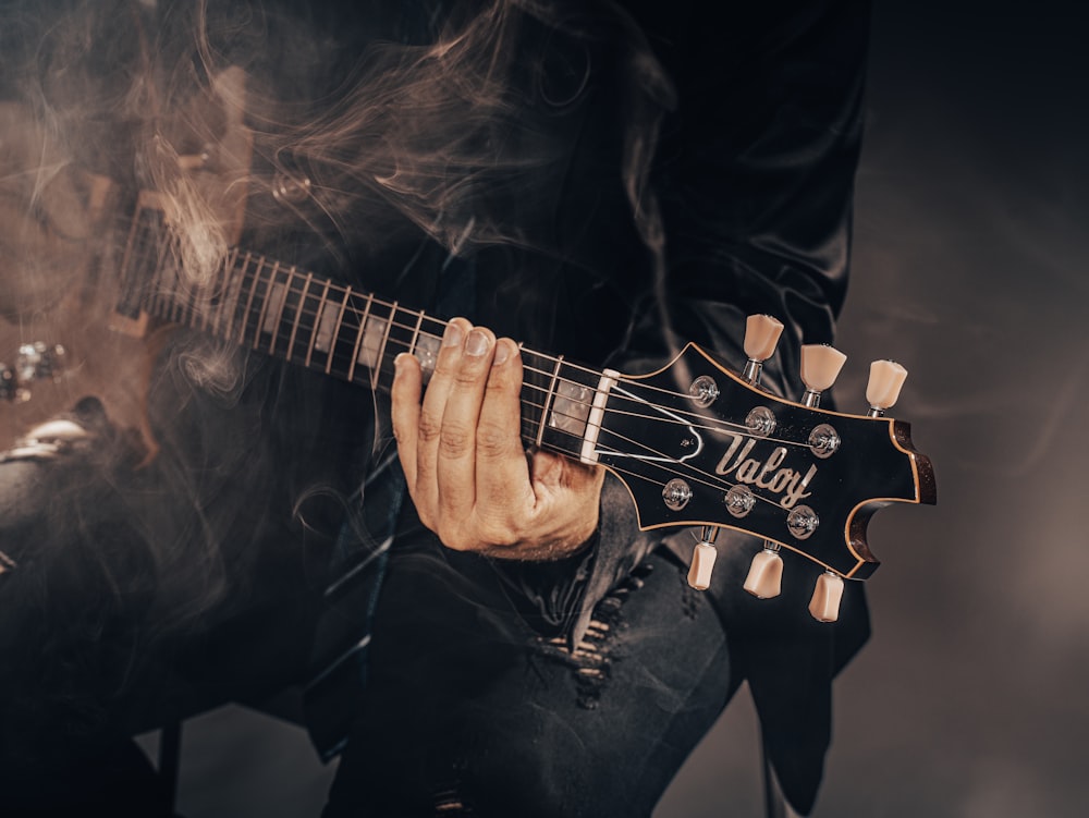a man playing a guitar with smoke coming out of his mouth