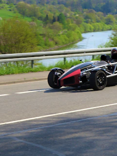 A Ferrari F8 cruising through a scenic alpine valley with vibrant greenery.