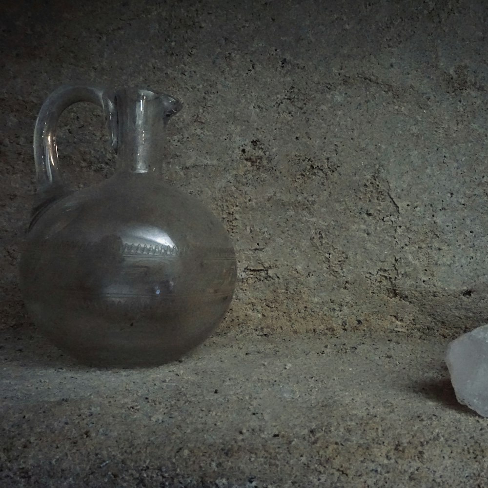 a silver vase sitting on top of a counter next to a rock