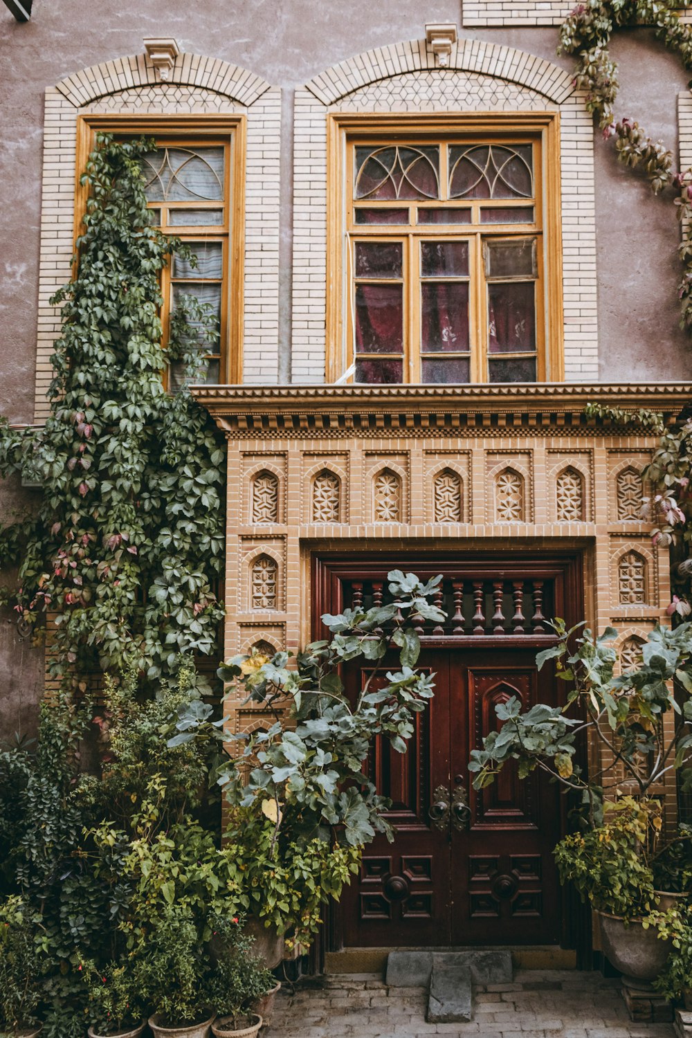 a building with a wooden door surrounded by plants