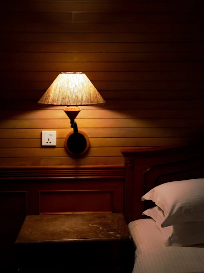 A softly glowing ceramic bedside lamp casting a warm light on a rustic wooden nightstand.