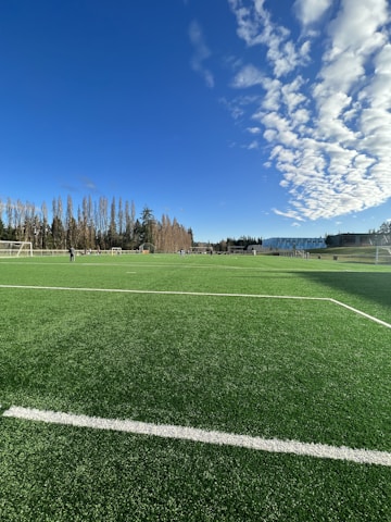 A vibrant football field with players practicing together under a clear blue sky.