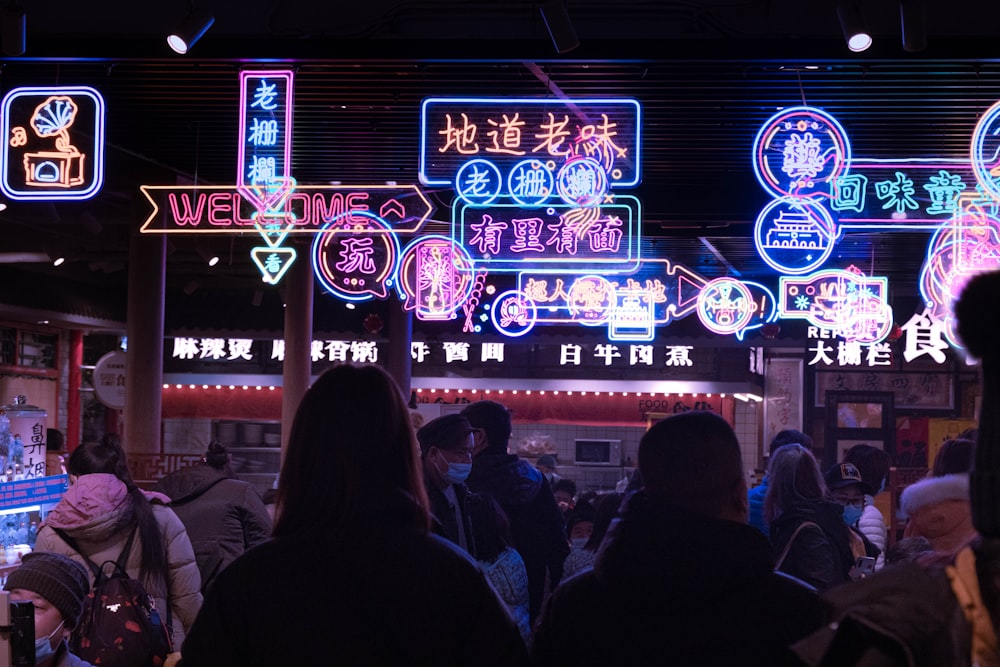 a group of people standing in front of neon signs