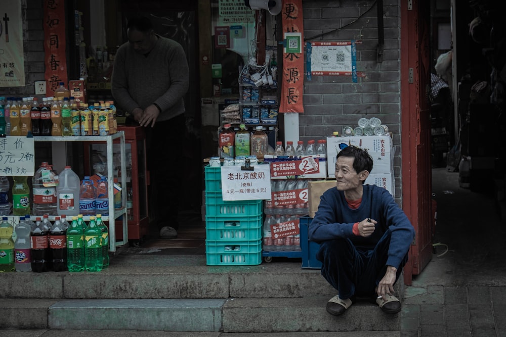 a man sitting on a step in front of a store