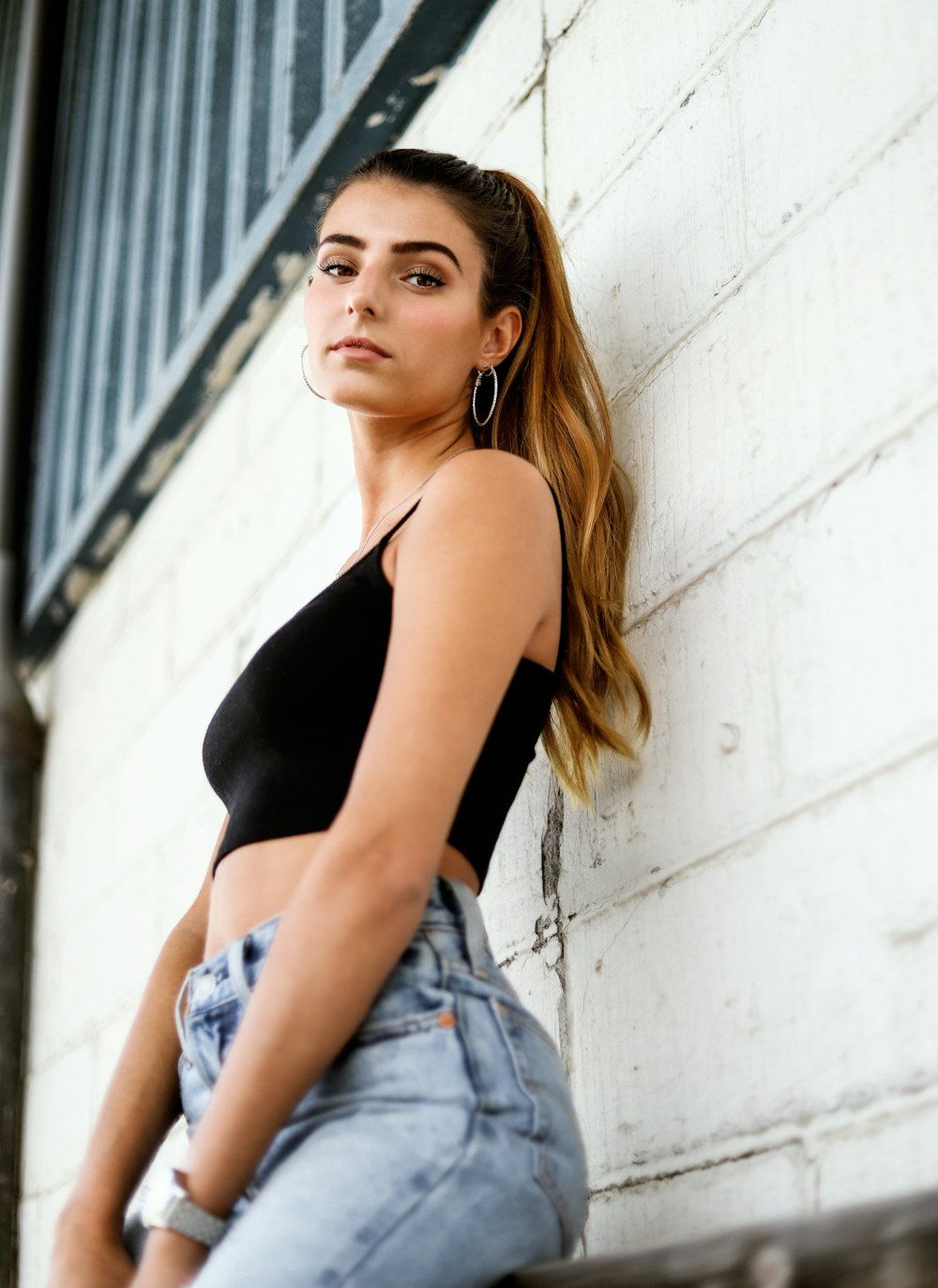 a beautiful young woman leaning against a wall