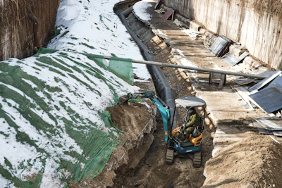 Excavator digging a foundation trench on a construction site in Telč.