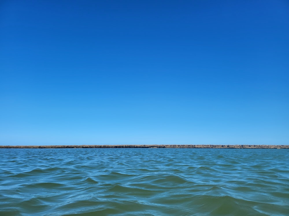 a large body of water sitting under a blue sky