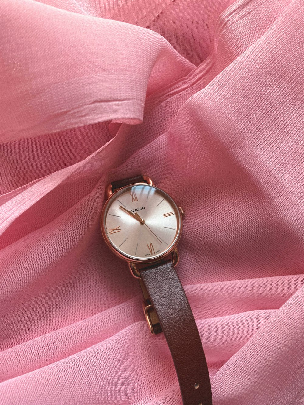 a watch sitting on top of a pink cloth