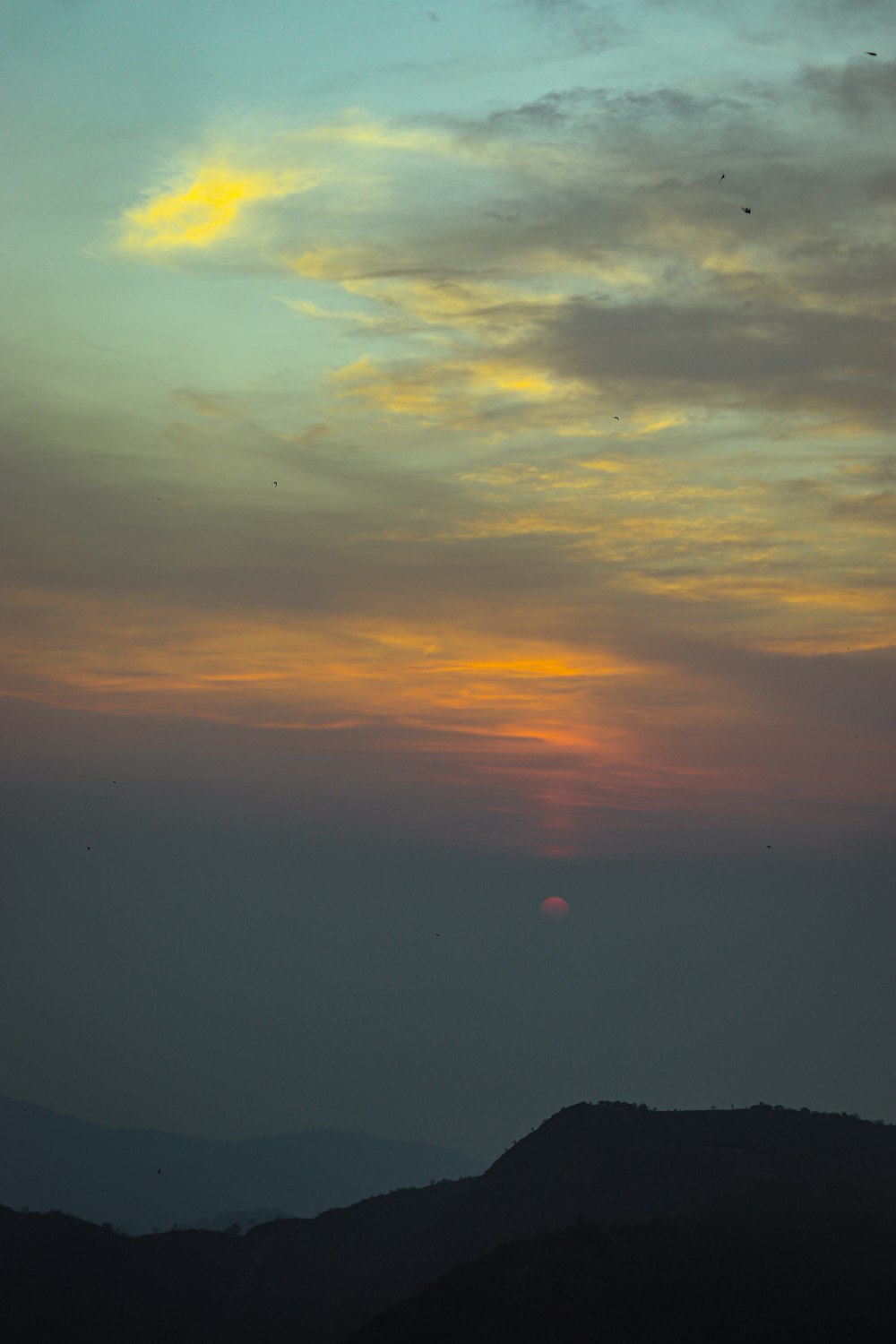 the sun is setting over a mountain range