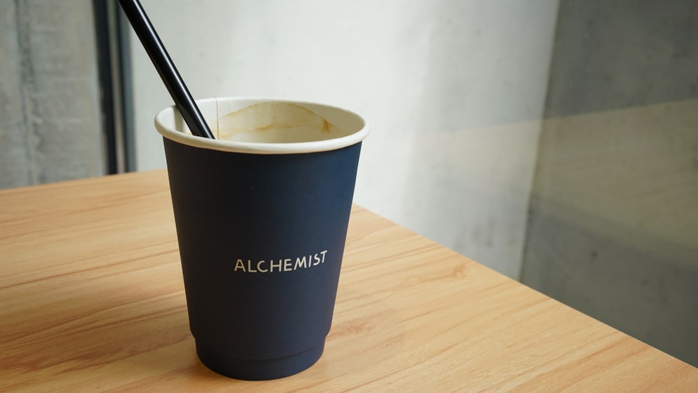 a black cup with a straw in it sitting on a table