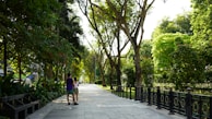 A candid photo of a couple walking hand in hand through a sunlit park.