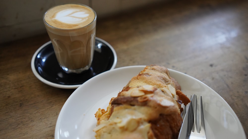 a white plate topped with a piece of cake next to a cup of coffee