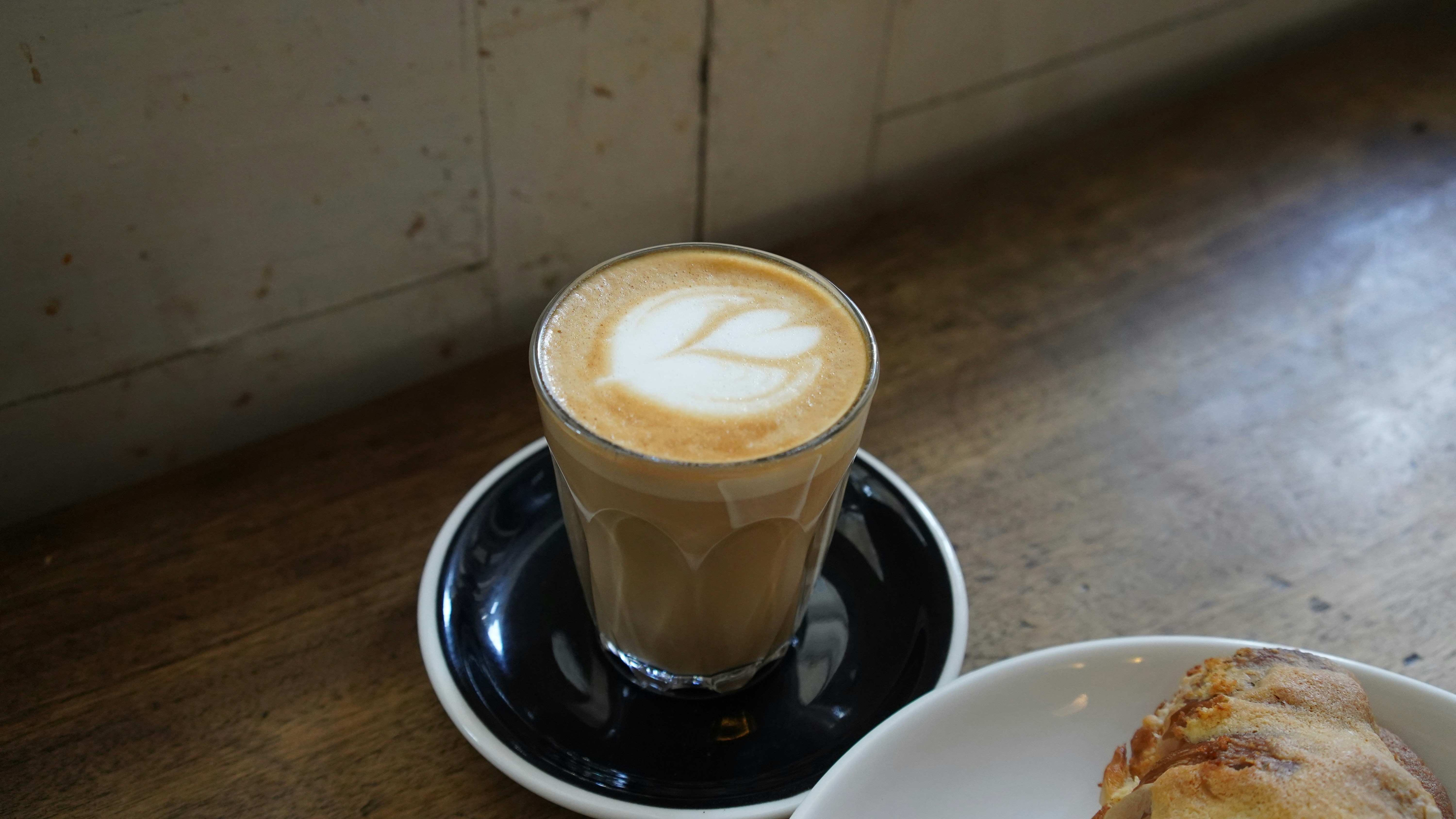 Glass of latte with a pastry on a cafe table