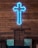 A neon blue cross is mounted on a wooden wall, above a wooden pulpit, which also has a carved cross on its front. The setting suggests an indoor religious space with wooden pews visible.