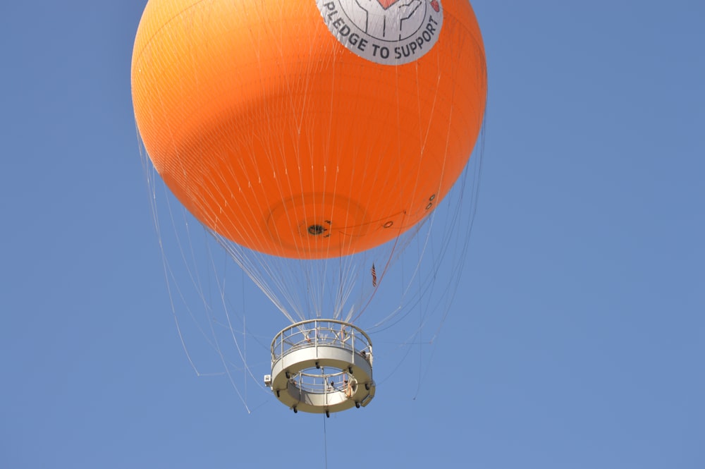 a large orange balloon flying through a blue sky