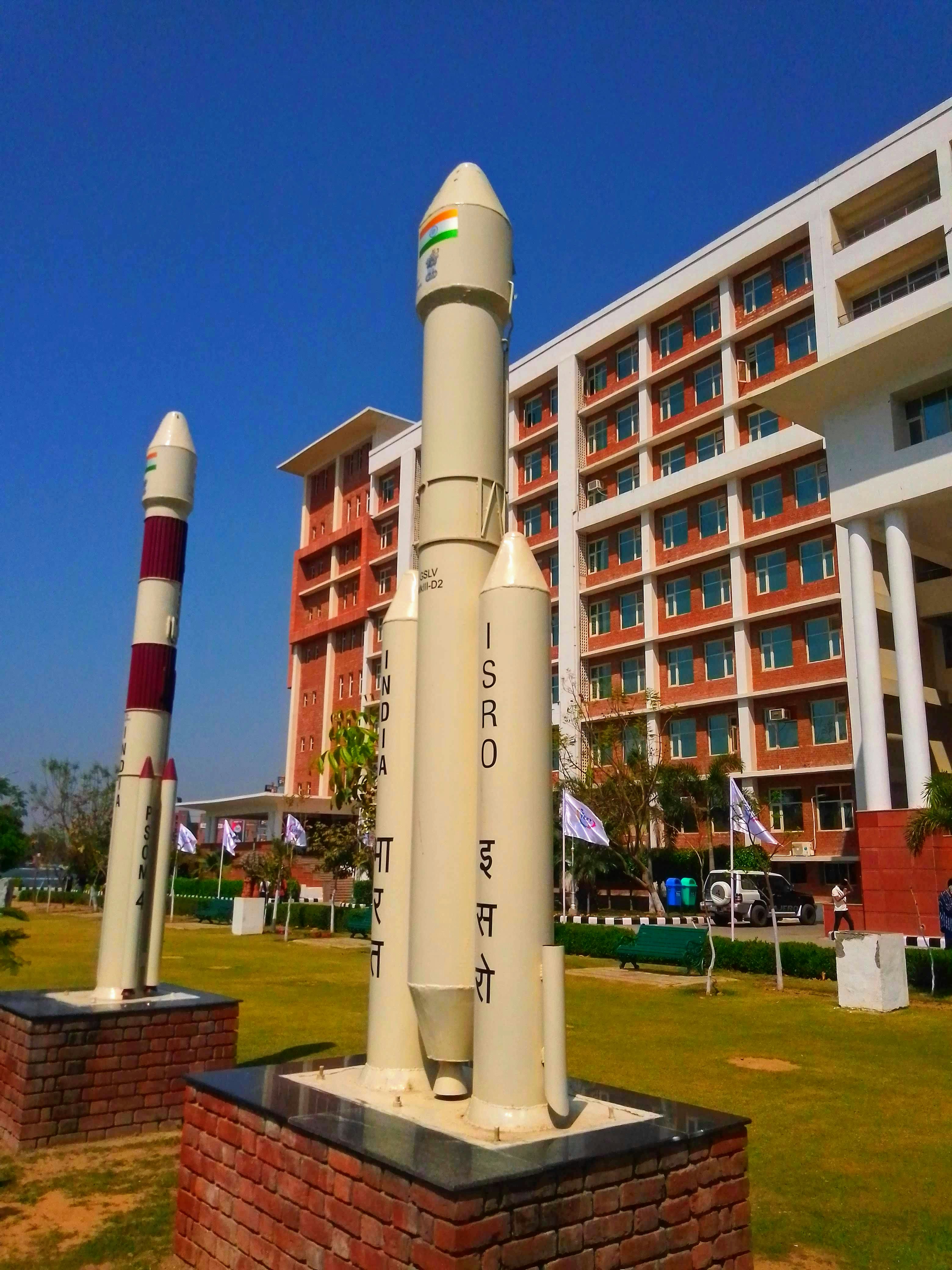 This image was captured inside the campus of Chandigarh University, India. The building behind is Kalpana Chawala Research Center. The image shows 2 rockets builted by ISRO in past years the one in white is GSLV mk.III.