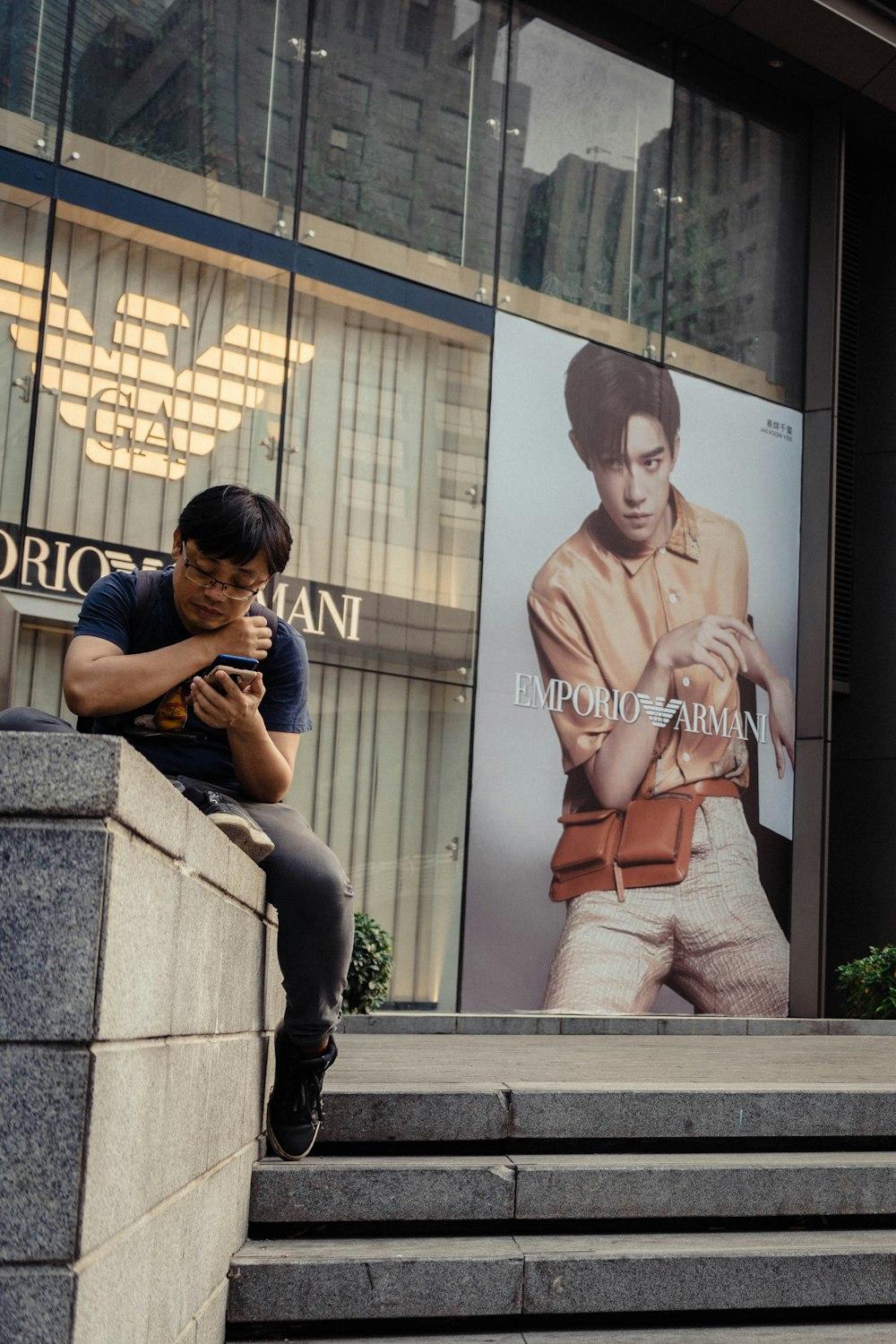 a man sitting on a ledge looking at his cell phone