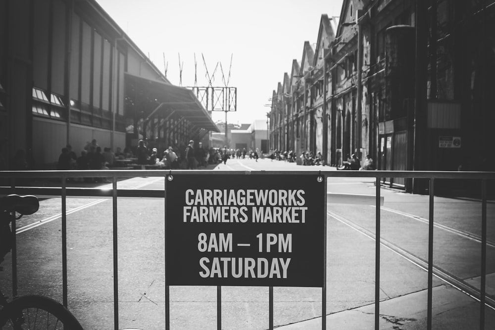 a black and white photo of a sign on a fence