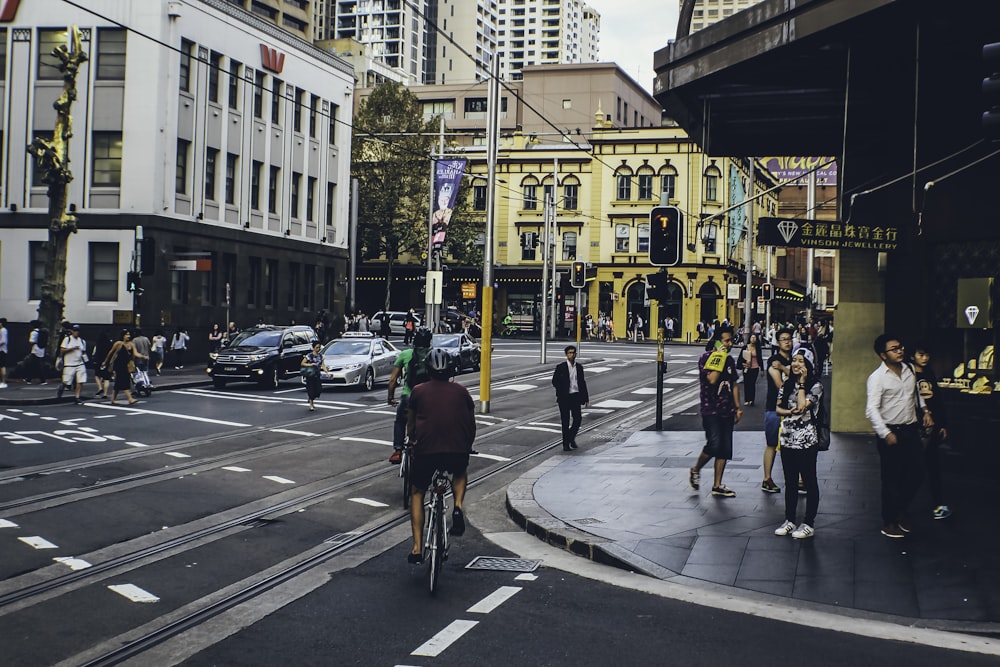 a man riding a bike down a street next to tall buildings