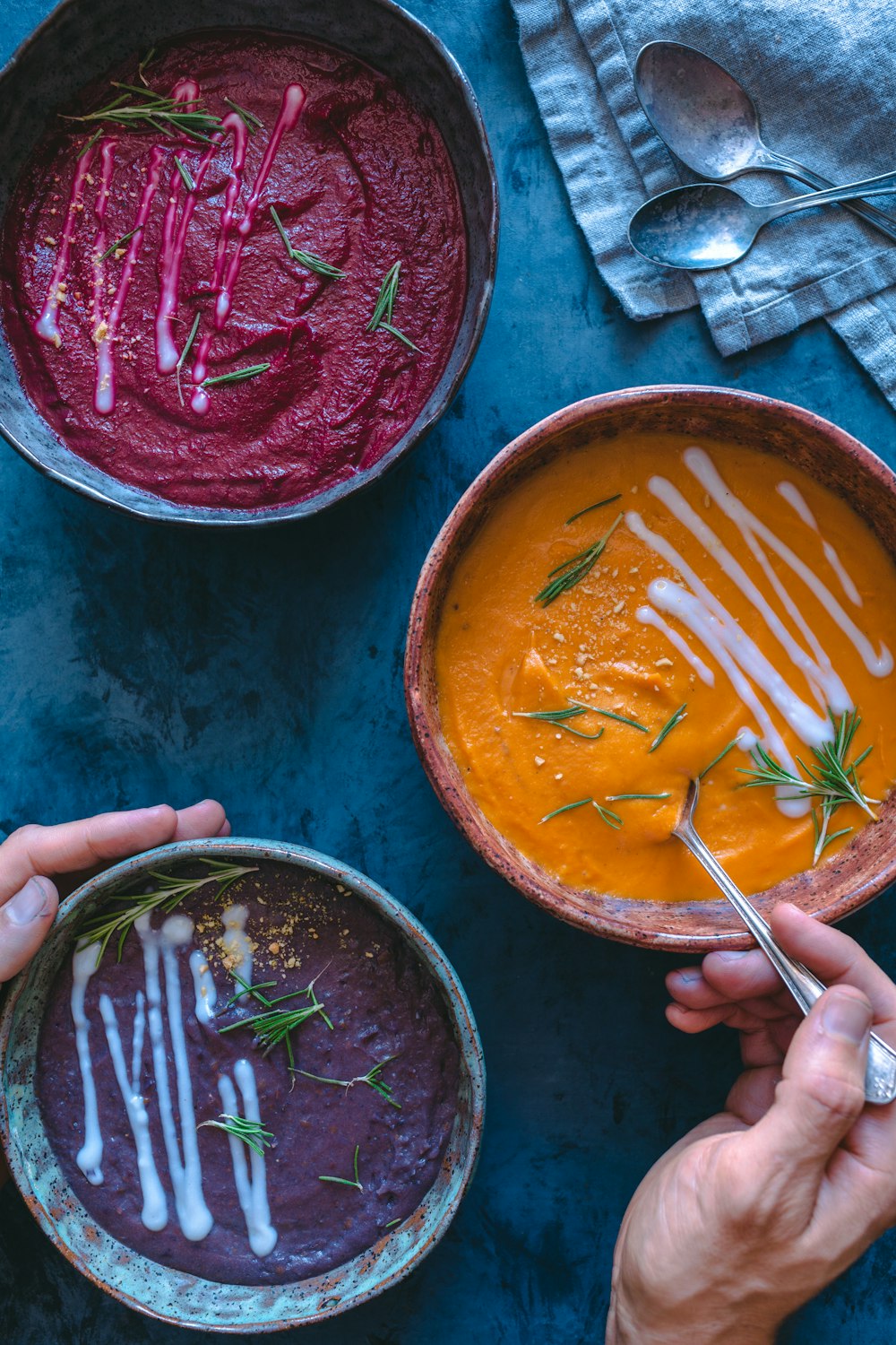 three bowls of different colored soups on a table