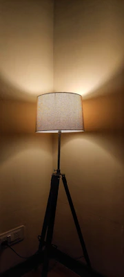 A sleek tripod standing lamp casting soft light in a minimalist living room with neutral tones.